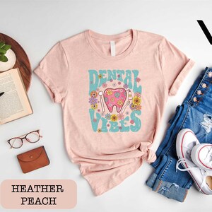 a pink shirt with a pink elephant on it next to a pair of jeans and