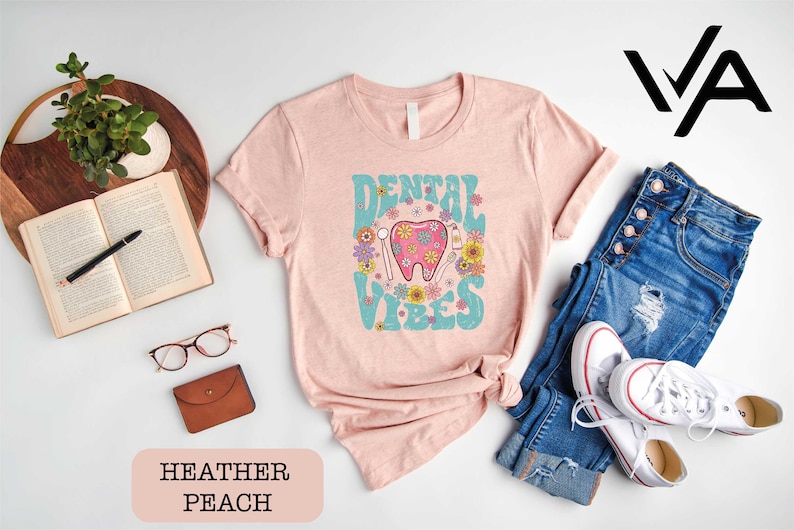 a pink shirt with a pink elephant on it next to a pair of jeans and