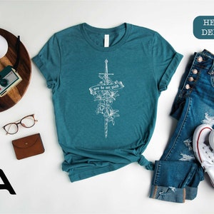 a t - shirt with a cross on it next to a pair of jeans and