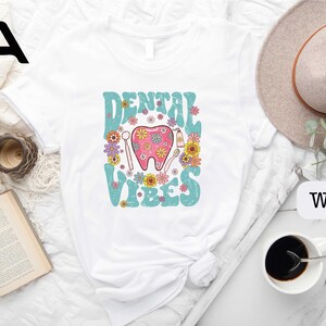 a white shirt with a pink tooth and flowers on it