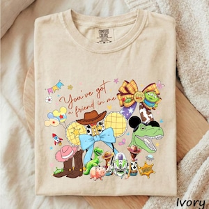 A beige t-shirt with a colorful graphic design featuring various cartoon characters and a message.