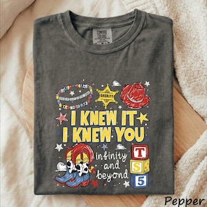 A gray t-shirt with a colorful graphic design featuring a cowboy hat, star, and various cartoon-style elements.