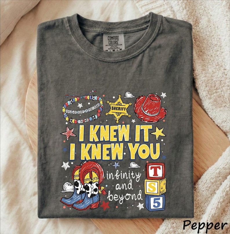 A gray t-shirt with a colorful graphic design featuring a cowboy hat, star, and various cartoon-style elements.