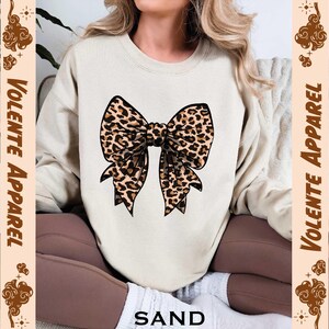 a woman wearing a sweater with a leopard print bow on it