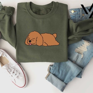 a brown dog laying on top of a green shirt