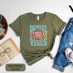 a shirt that says dental vibes on it next to a pair of jeans and