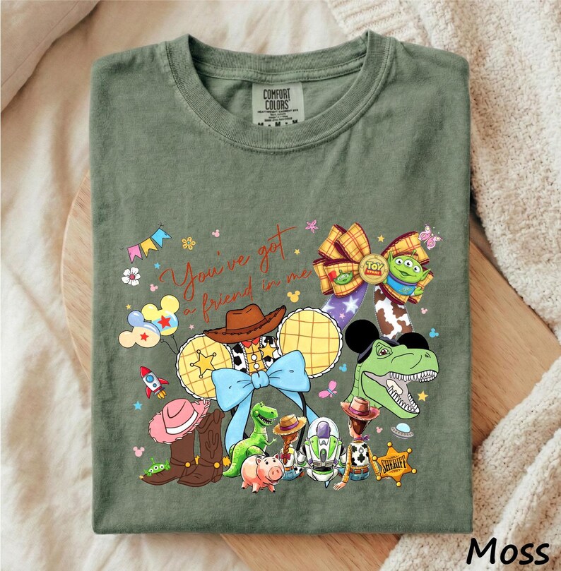 A green t-shirt with a colorful graphic design featuring characters from the Toy Story movie, including Woody, Buzz Lightyear, and other beloved characters.