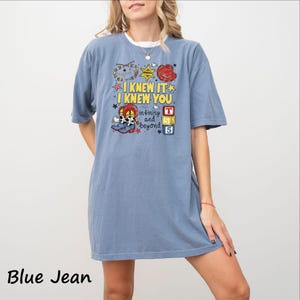 A woman wearing a blue t-shirt with a cartoon character and text printed on it.