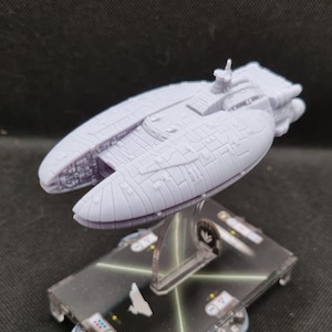 Könnte beinhalten: Ein weißes Plastikmodell eines Star Wars Raumschiffs, der Nebulon-B Fregatte, auf einem schwarz-weißen Spielbrett mit einem durchsichtigen Plastikständer.