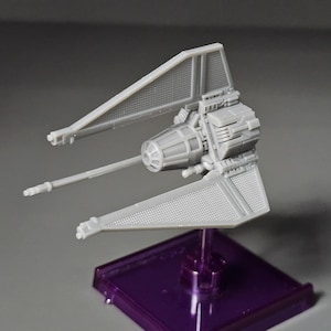May include: A gray TIE Interceptor starship model with a detailed design. The model is mounted on a purple base.