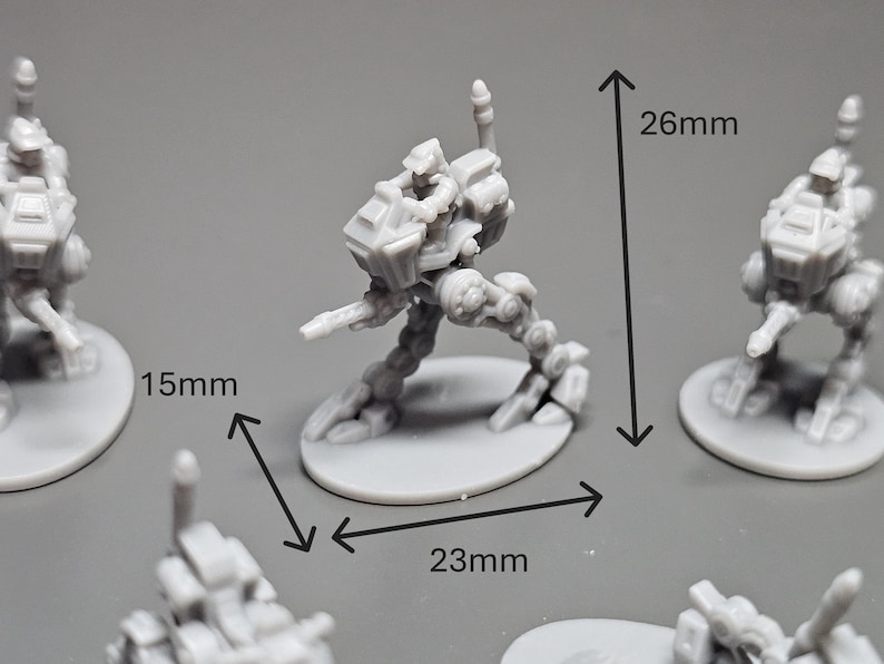 May include: A gray miniature robot figure, 26mm tall and 23mm wide, with a 15mm base. The figure is posed in a dynamic stance, suggesting movement. Several similar figures are visible, indicating a set or collection.