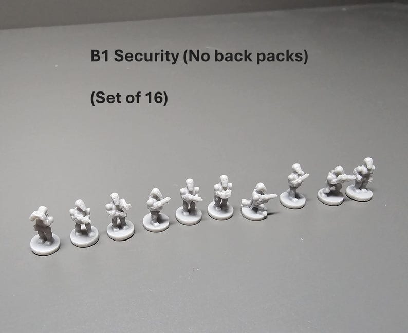 K&ouml;nnte beinhalten: Ein Satz von 16 grauen Miniaturfiguren mit der Aufschrift "B1 Security (No back packs)". Die Figuren befinden sich in verschiedenen Posen, einige stehen und andere knien, und scheinen Waffen zu halten. Die Figuren stehen auf kleinen kreisf&ouml;rmigen Sockeln.