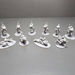 May include: A collection of small, gray, miniature robot figures. Some are upright on circular bases, while others are lying down on oval bases. The robots have detailed mechanical designs, suggesting a science fiction or fantasy theme.