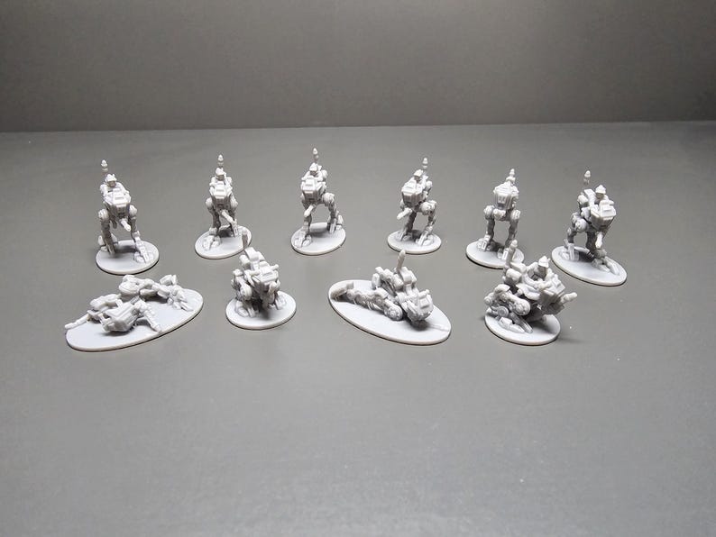 May include: A collection of small, gray, miniature robot figures. Some are upright on circular bases, while others are lying down on oval bases. The robots have detailed mechanical designs, suggesting a science fiction or fantasy theme.