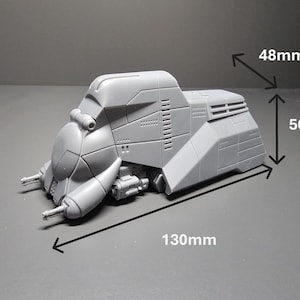 May include: A gray, futuristic model of a vehicle, measuring 130mm long, 50mm high, and 48mm wide. The model has a detailed design with various panels, vents, and protrusions, suggesting a sci-fi or military theme.