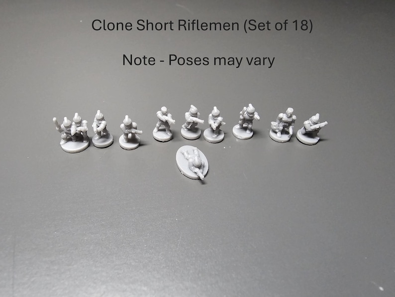 May include: A collection of 18 miniature Clone Short Riflemen figures. The figures are light grey and are on small, round bases. The text "Clone Short Riflemen (Set of 18)" and "Note - Poses may vary" are visible.
