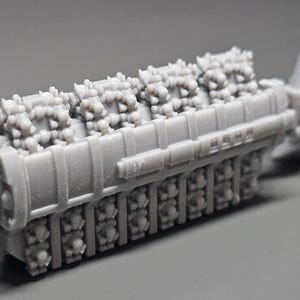 May include: A gray model of an engine, featuring detailed components. The engine has a rectangular body with multiple cylinders and intricate surface details. The model is likely for hobbyists or collectors.
