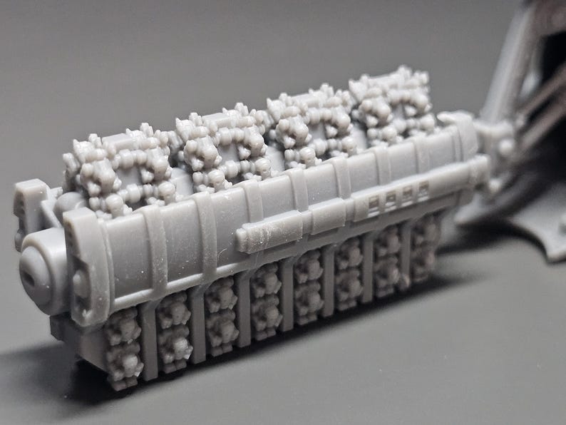 May include: A gray model of an engine, featuring detailed components. The engine has a rectangular body with multiple cylinders and intricate surface details. The model is likely for hobbyists or collectors.