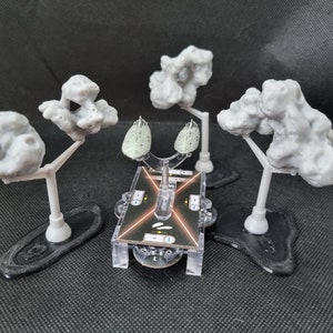 May include: Four grey 3D printed rock formations on stands, with two green spaceships on a clear plastic base. The base has a black and orange design with the text "2" on it.