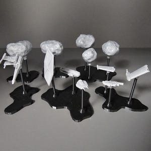 Könnte beinhalten: Eine Sammlung weißer Miniatur-Raumschiffmodelle, darunter X-Wings und TIE-Fighter, werden auf schwarzen, unregelmäßig geformten Sockeln präsentiert. Einige Modelle werden von kugelförmigen, wolkenartigen Formationen begleitet. Die Modelle sind auf dünnen, schwarzen Stäben montiert.