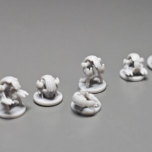 Pode incluir: V&aacute;rias pequenas figuras em miniatura cinza claro de criaturas fant&aacute;sticas. Cada figura est&aacute; em uma pequena base redonda. As criaturas t&ecirc;m uma variedade de formas, algumas com ap&ecirc;ndices semelhantes a garras e outras com corpos arredondados. As figuras est&atilde;o dispostas em uma superf&iacute;cie cinza.