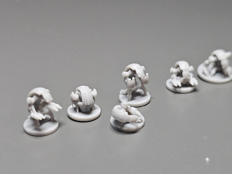 Pode incluir: V&aacute;rias pequenas figuras em miniatura cinza claro de criaturas fant&aacute;sticas. Cada figura est&aacute; em uma pequena base redonda. As criaturas t&ecirc;m uma variedade de formas, algumas com ap&ecirc;ndices semelhantes a garras e outras com corpos arredondados. As figuras est&atilde;o dispostas em uma superf&iacute;cie cinza.