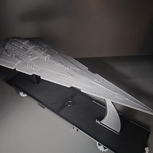Könnte beinhalten: Ein weißes 3D-gedrucktes Modell eines Star Destroyer Raumschiffs auf einem schwarzen Display-Ständer.