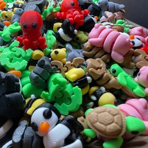 K&ouml;nnte beinhalten: Eine Sammlung von bunten 3D-gedruckten Figuren, darunter ein roter Oktopus, ein rosa Seepferdchen, eine gr&uuml;ne Schildkr&ouml;te, ein Pinguin und eine Vielzahl anderer Meeresbewohner. Die Figuren sind aus Kunststoff und etwa 5 cm hoch.