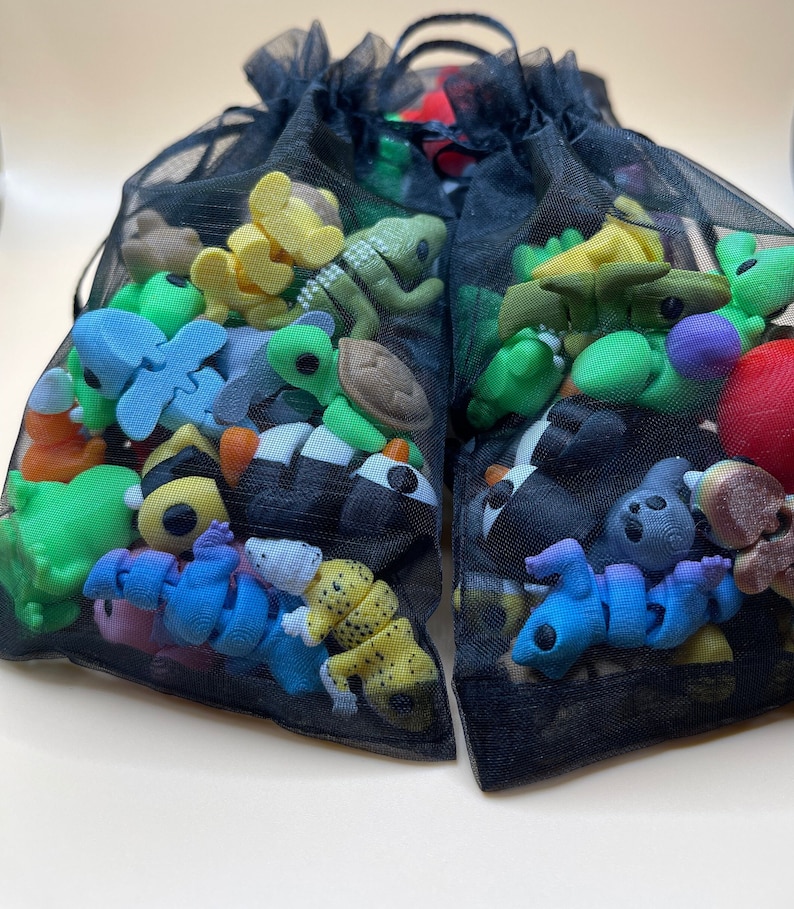 K&ouml;nnte beinhalten: Zwei schwarze Netztaschen gef&uuml;llt mit einer Vielzahl von bunten kleinen Gummispielzeug. Die Spielzeuge sind in Form von Tieren, Insekten und anderen Objekten.