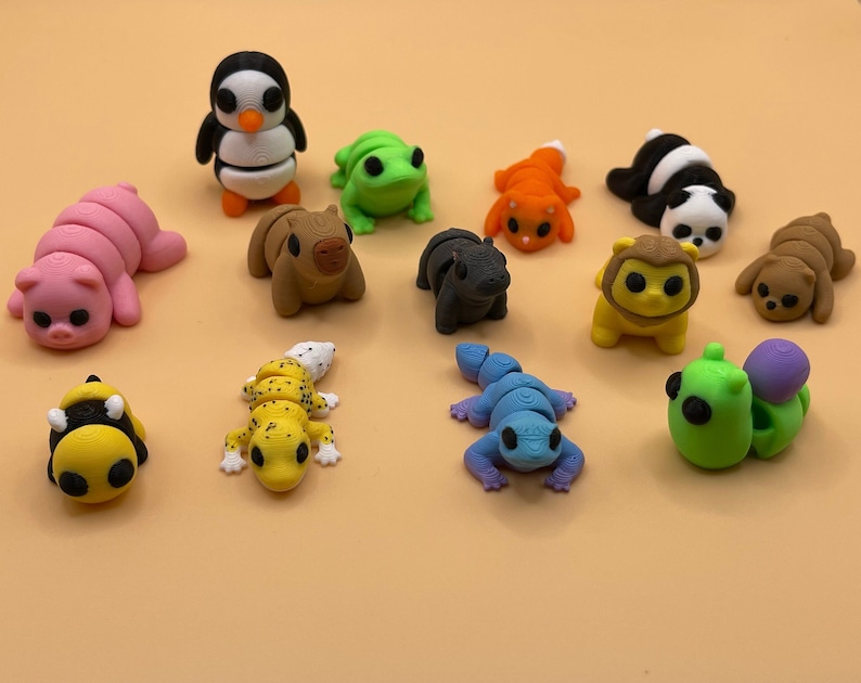 K&ouml;nnte beinhalten: Eine Sammlung von 14 kleinen, bunten Tierfiguren, darunter ein Pinguin, ein Frosch, eine Raupe, eine Biene, ein Gecko und eine Schnecke. Die Figuren sind aus Kunststoff und etwa 5 cm gro&szlig;.