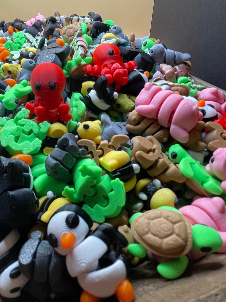 K&ouml;nnte beinhalten: Eine Sammlung von bunten 3D-gedruckten Figuren, darunter ein roter Oktopus, ein rosa Seepferdchen, eine gr&uuml;ne Schildkr&ouml;te, ein Pinguin und eine Vielzahl anderer Meeresbewohner. Die Figuren sind aus Kunststoff und etwa 5 cm hoch.