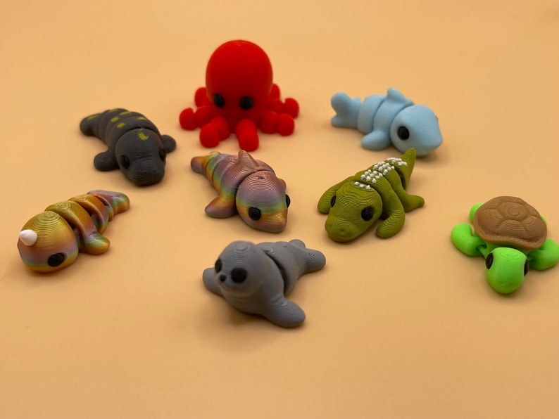 K&ouml;nnte beinhalten: Ein Set aus acht farbenfrohen, handbemalten Meereslebewesen-Figuren. Die Figuren umfassen einen Oktopus, einen Delfin, einen Hai, eine Schildkr&ouml;te, eine Robbe, ein Eidechse und zwei Fische. Die Figuren sind aus einem glatten, strapazierf&auml;higen Material gefertigt und perfekt, um jedem Wohndekor einen Hauch von Verspieltheit zu verleihen.