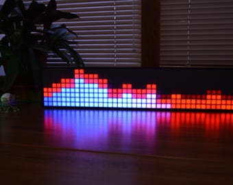 May include: A black rectangular audio visualizer with a series of blue and red lights that change in height to represent sound levels.