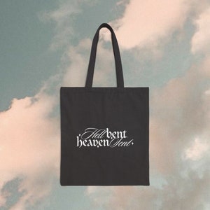 Könnte beinhalten: Eine schwarze Tragetasche mit weißem Text, der "Hell bent heaven sent" lautet.