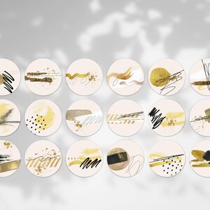 May include: Eighteen circular stickers with abstract art designs. Each sticker has a beige base with gold, black, and white brushstrokes, lines, and splatters. Some stickers include text. The overall theme is modern and artistic.