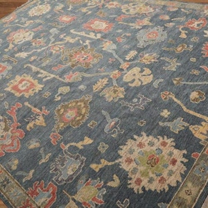 Peut inclure: Un tapis bleu avec un motif persan traditionnel présentant des motifs floraux complexes dans des tons de rouge, beige et vert. Le tapis a une bordure frangée.