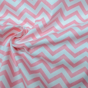 Könnte beinhalten: Rosa-weißes Chevron-Musterstoff. Der Stoff ist gefaltet und hat eine weiche, strukturierte Haptik.