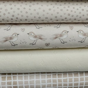 Könnte beinhalten: Vier verschiedene Stoffmuster in verschiedenen Beigetönen. Das oberste Muster zeigt ein kleines, sich wiederholendes Muster aus grauen Punkten. Das zweite Muster zeigt ein sich wiederholendes Muster aus kleinen grauen Vögeln mit Herzen. Das dritte Muster ist ein schlichter, strukturierter beigefarbener Stoff. Das unterste Muster zeigt ein sich wiederholendes Muster aus kleinen grauen Quadraten.