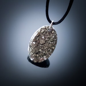 May include: A silver chain necklace with a pendant made of a clear resin filled with a sparkly gold material.