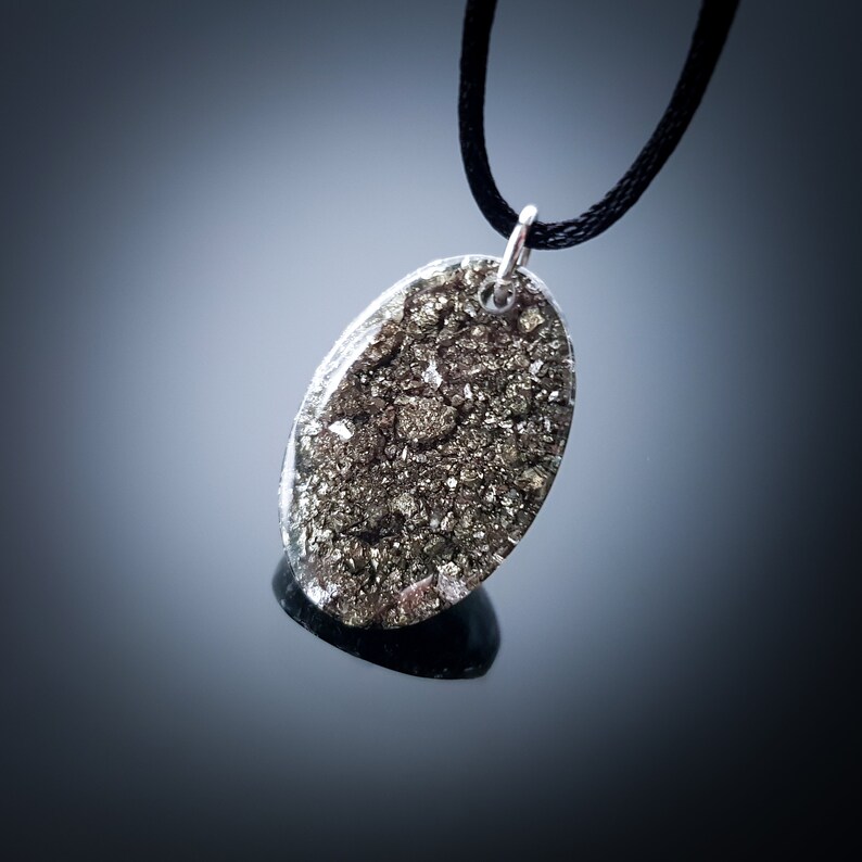 May include: A silver chain necklace with a pendant made of a clear resin filled with a sparkly gold material.