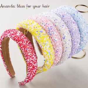 Puede incluir: Conjunto de seis diademas brillantes de colores. Las diademas están hechas de un material suave y flexible y están decoradas con purpurina iridiscente. Las diademas están dispuestas en orden de arcoíris, comenzando por el rojo y terminando por el morado.