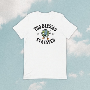 May include: White t-shirt with a black graphic of a cartoon Earth singing and the text "Too Blessed To Be Stressed".