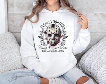 May include: White hoodie with a graphic of Jason Voorhees's hockey mask, the text "Jason Voorhees", and the text "Camp Crystal Lake Hide and Seek Champion".