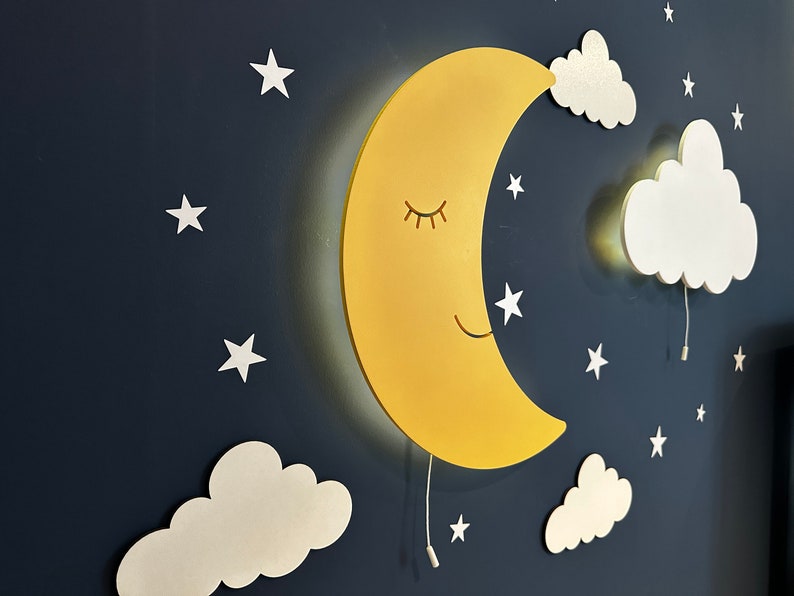 May include: A yellow crescent moon wall light with a smiling face and closed eyes, surrounded by white clouds and stars on a dark blue background.