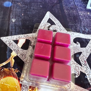 May include: Six square wax melts in a clear plastic packaging. The wax melts are a deep, rich magenta colour.