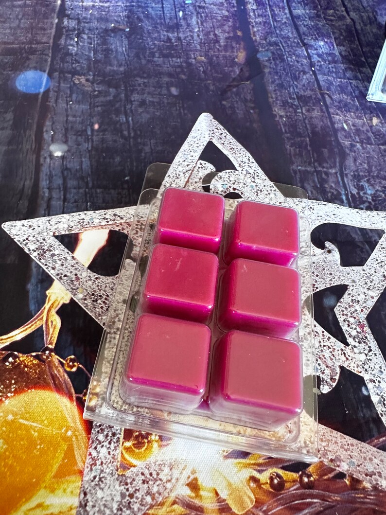 May include: Six square wax melts in a clear plastic packaging. The wax melts are a deep, rich magenta colour.