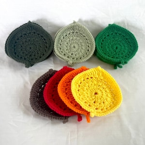 May include: A set of crocheted coasters in various colors, including green, yellow, orange, red, and brown. The coasters are stacked in a rainbow pattern.