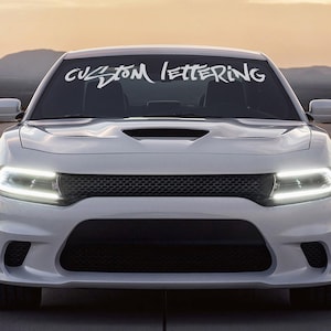 May include: White car with a custom lettering decal on the windshield that says "CUSTOM LETTERING".