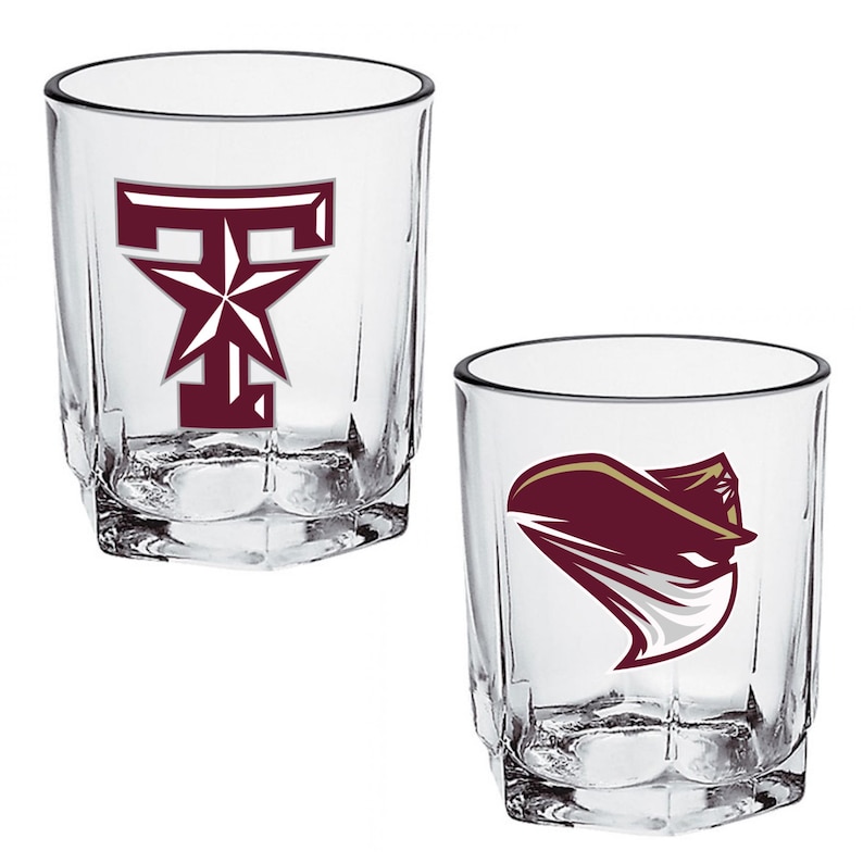 May include: Two clear, faceted lowball glasses. One glass features a maroon "T" with a star, the other a maroon and gold graphic. Both glasses are empty and ready for use.