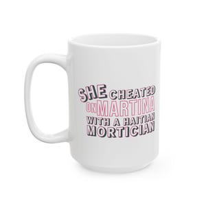 White ceramic mug with bold pink and black text reading “She cheated on Martina with a Haitian mortician,” referencing a Real Housewives of Miami quote.